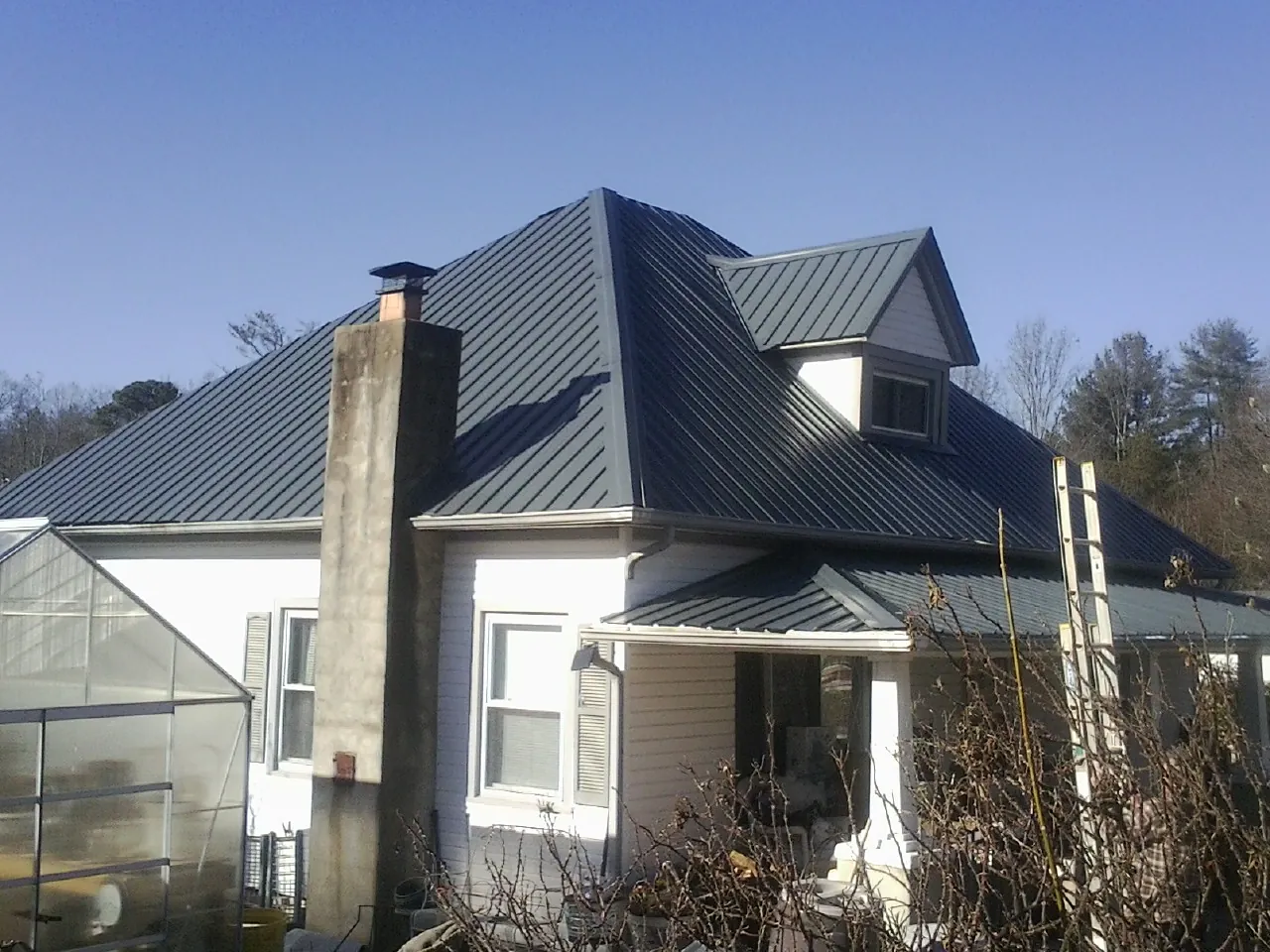 Dark blue standing seam metal roof on a white farmhouse with dormer — Slate & Tile Roof Repair by Roofing Brothers in Minerva