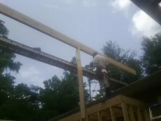 Carpenter setting a ridge beam over a new addition frame in Minerva