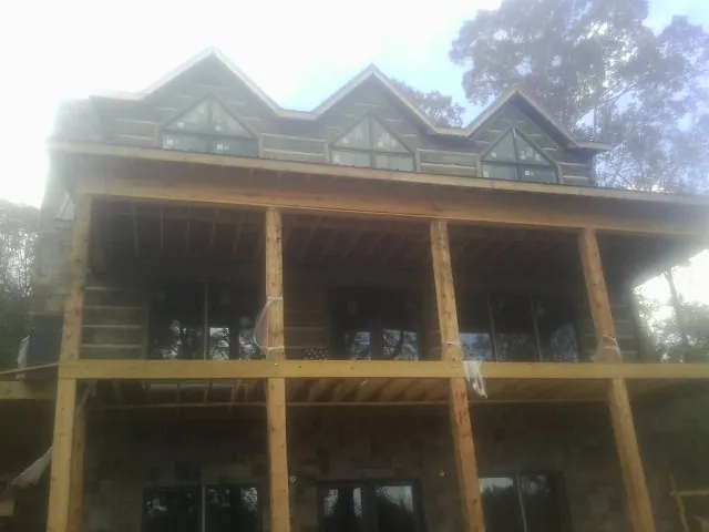 Dormers and porch framing on a large log home under construction — Roof Coating work by our crew in Minerva