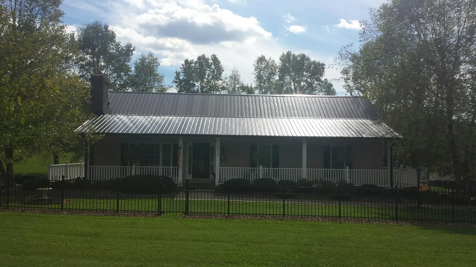 Gray metal roof on a brick ranch with a full width front porch — Gutter Guard Installation work by our crew in Minerva