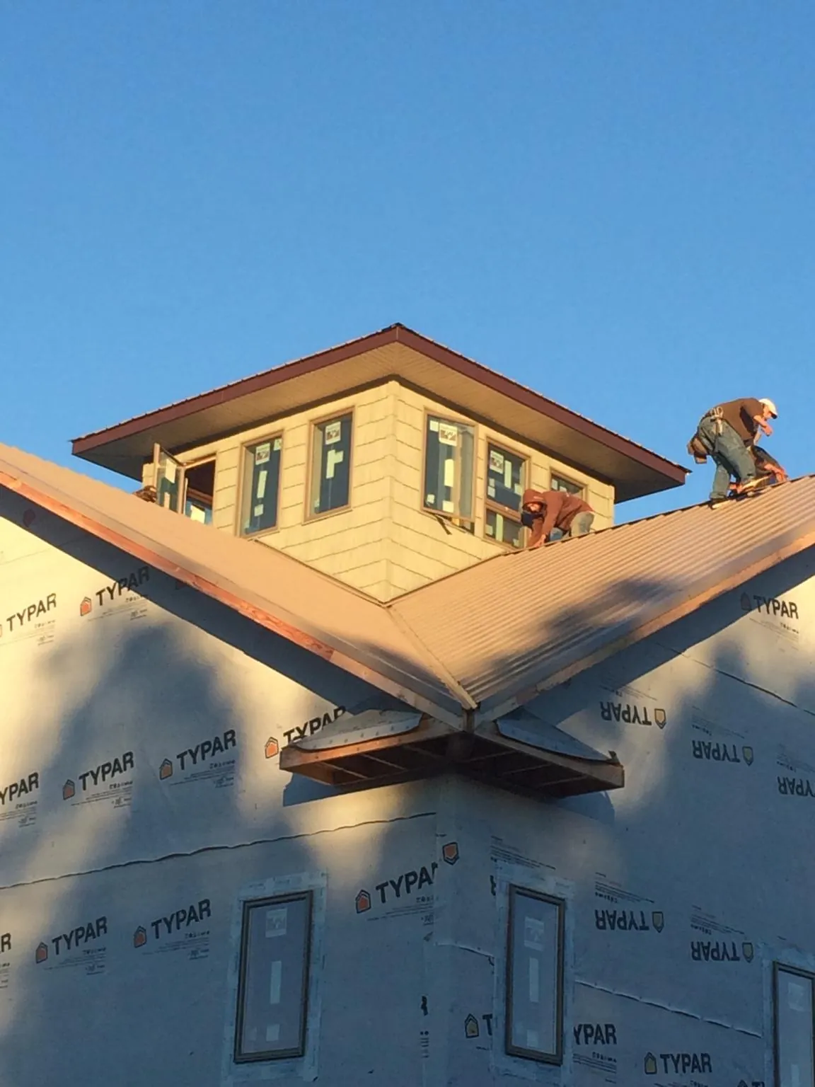 Roofers working around a rooftop cupola on a new metal roof at sunset — Roof Waterproofing in Minerva by Roofing Brothers
